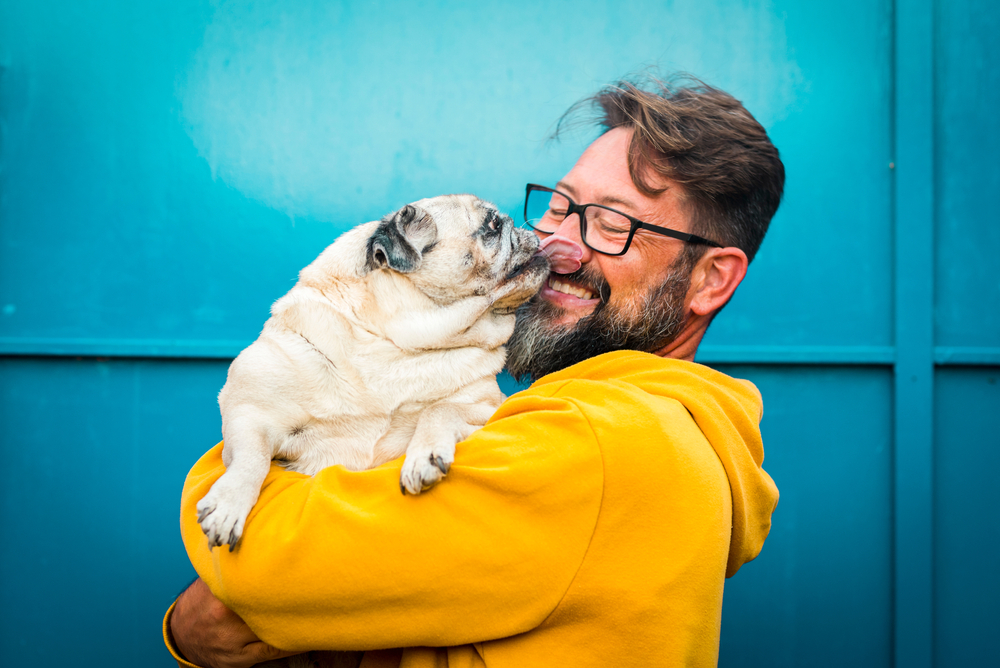 Adult man joyfully bonding with his dog outdoors — the special friendship between pets and owners